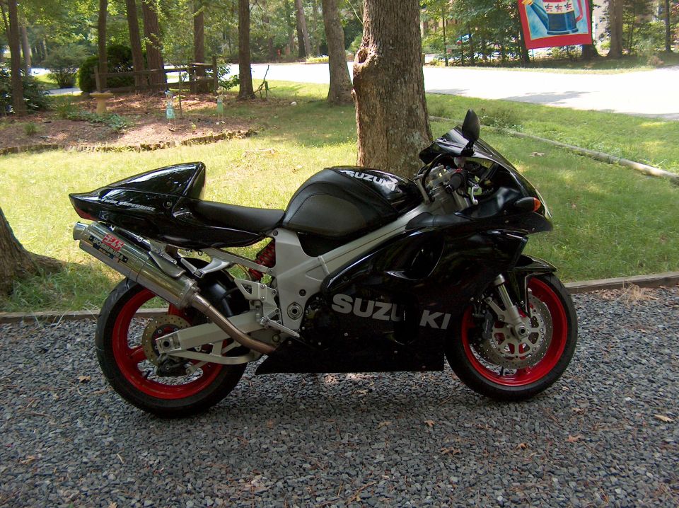 Black 2002 Suzuki TL1000R motorcycle with red wheels parked on gravel