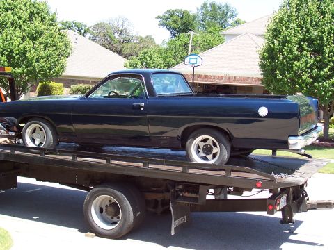 1969 Ford Ranchero - A black 1969 Ford Ranchero is loaded onto a flatbed tow truck.