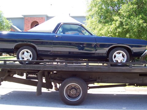 1969 Ford Ranchero - A dark blue 1969 Ford Ranchero is loaded onto a flatbed tow truck for transport.