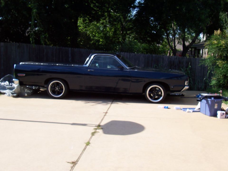 Dark blue Ford Ranchero coupe-utility in profile on a driveway with black wheels.