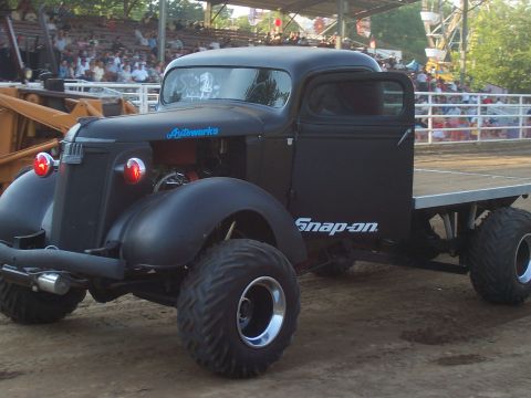 1994 Ford F-150 - Modified vintage truck with "Snap-on" branding and oversized tires sits at an outdoor event.