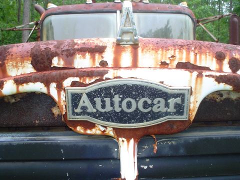 1981 Ford Bronco - Close-up of a heavily rusted Autocar truck's front grille and hood ornament.