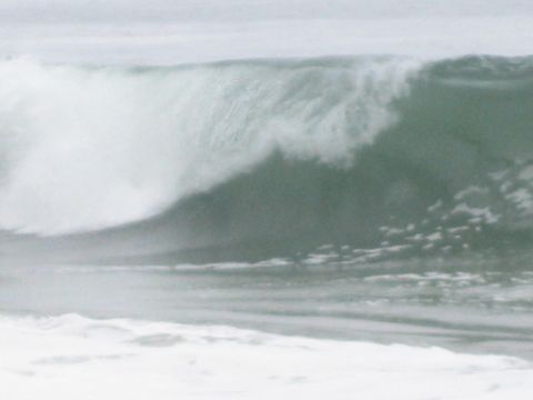 1990 Ford Bronco - powerful ocean wave curls and breaks, throwing whitewater and spray across a grey sea.
