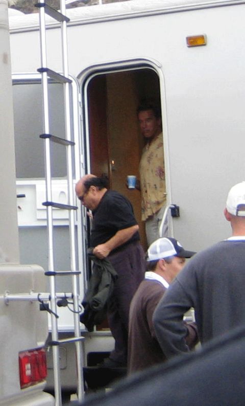 1990 Ford Bronco - man in black steps down from a white trailer while another in a floral shirt stands in the doorway.