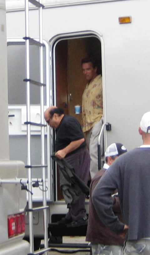 1990 Ford Bronco - man carrying a folded jacket leaves a white trailer as another in a floral shirt stands inside.