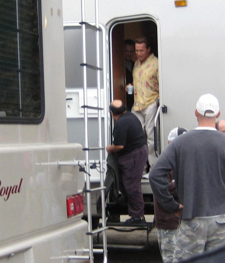 People gathered at the steps of a white trailer labeled 'Royal' with a man in a floral shirt