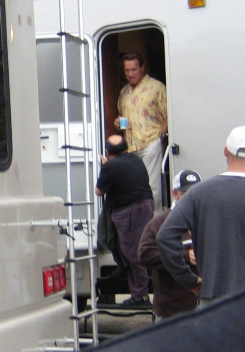 1990 Ford Bronco - man in a yellow floral shirt holds a cup in a white trailer's doorway while others stand at the steps.