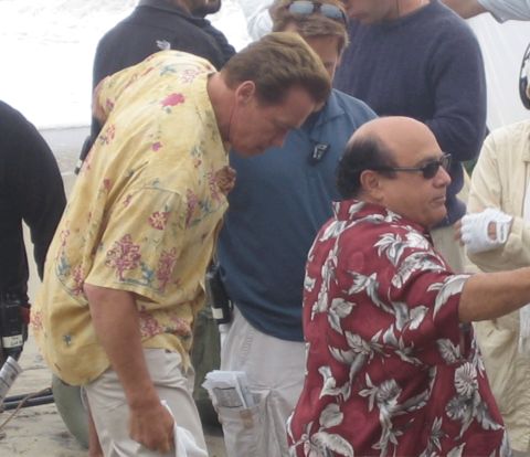 1990 Ford Bronco - man in a yellow floral shirt and a man in a red floral shirt with sunglasses stand close among an outdoor crowd.
