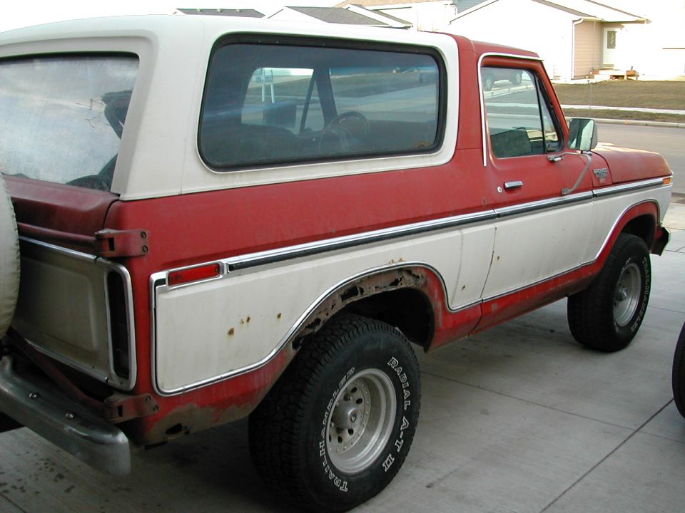 Passenger side of weathered red and white full-size Ford Bronco on a driveway