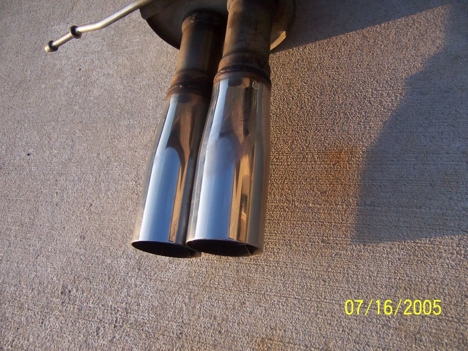 Dual chrome exhaust tips mounted on a concrete surface