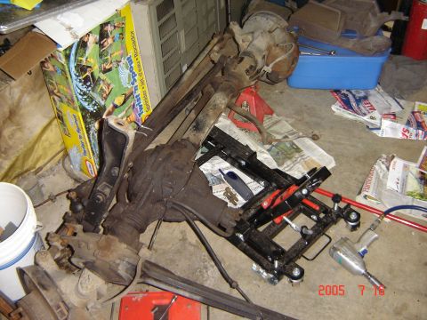 1993 Ford Bronco - Vehicle axle parts are scattered on the floor next to a toy box and a blue storage bin.