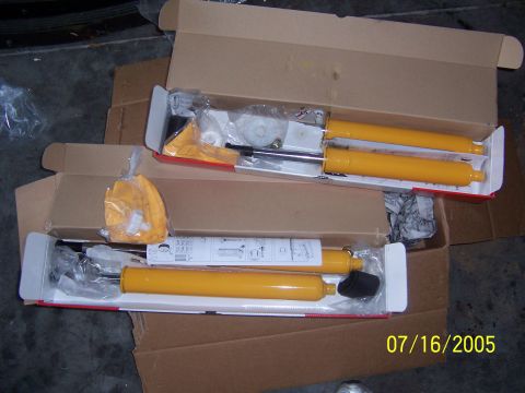 1994 Ford Probe - Two new yellow shock absorbers are shown in their original packaging, with installation instructions visible on one.