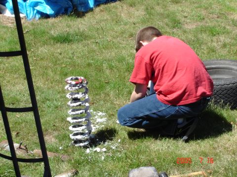 1993 Ford Bronco - A person is working on a coil spring in a grassy area next to a tire.