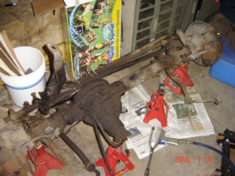 1993 Ford Bronco - A disassembled vehicle axle assembly is shown supported by red jack stands in a garage setting.