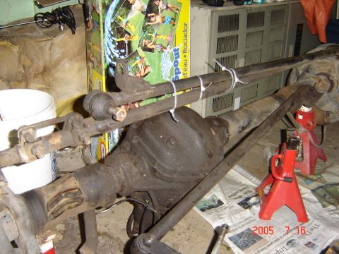 1993 Ford Bronco - Close-up of a vehicle's front axle and steering components, resting on jack stands.