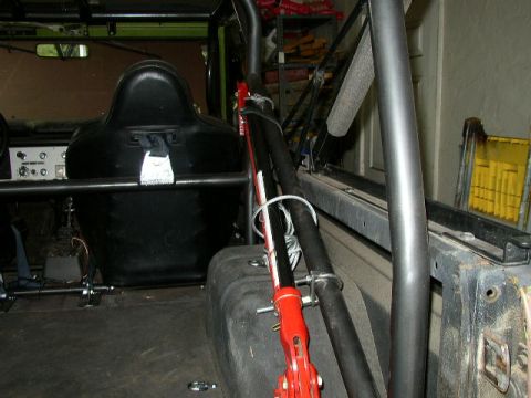 1995 Ford Bronco - The interior of a modified vehicle shows a racing seat and roll cage, with a red jack secured to the side.