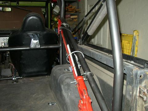 1995 Ford Bronco - The interior of a modified vehicle features a roll cage, racing seat, and a red jack secured to the side.