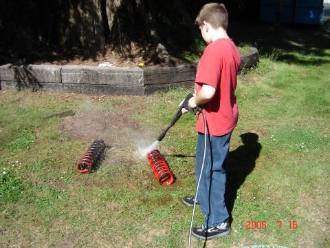 1993 Ford Bronco - Boy cleans coil springs with a pressure washer outdoors.
