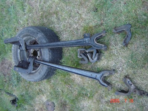 1993 Ford Bronco - Vehicle axle components and a spare tire are displayed on a grassy surface. Some parts have '50' stamped on them.