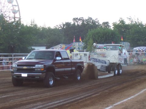 1994 Ford F-150 - A maroon 1999 Chevrolet Silverado truck competes in a pull event, dragging a trailer with "TERMINATOR" written on its side.