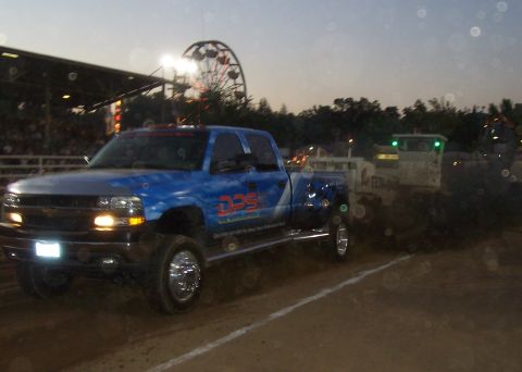 1994 Ford F-150 - A blue pickup truck with custom graphics is seen in a pull event, with a weight sled behind it.