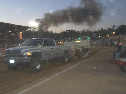 1994 Ford F-150 - A silver pickup truck emits black smoke while pulling a trailer at an outdoor event.