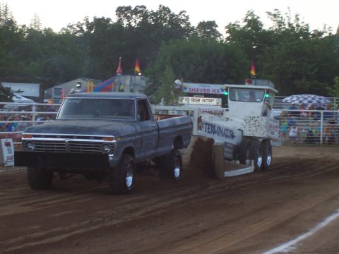 1994 Ford F-150 - A lifted 1975 Ford F-150 truck competes in a pull event, dragging a sled on a dirt track.