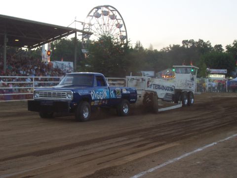 1994 Ford F-150 - A blue pickup truck, identified as a 1979 model, competes in a pulling event, dragging a trailer with "Terminator" graphics.
