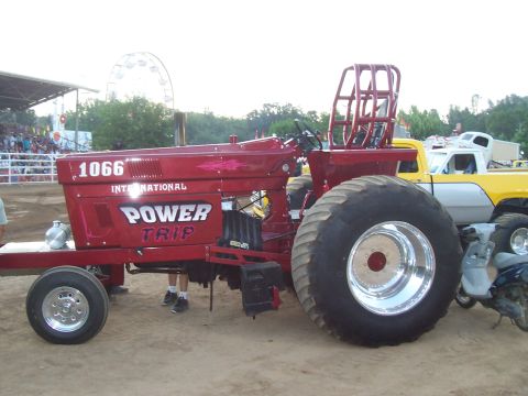 1994 Ford F-150 - A modified red tractor with "POWER TRIP" branding is parked next to a yellow and white pickup truck.