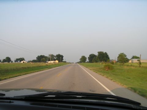 1993 Ford Taurus - Driving down a rural highway with green fields and farm buildings visible under a hazy sky.