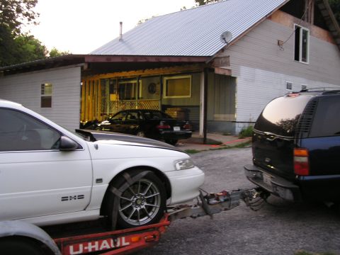 1993 Ford Taurus - 1993 Ford Taurus being transported on a trailer, with a dark SUV as the tow vehicle.