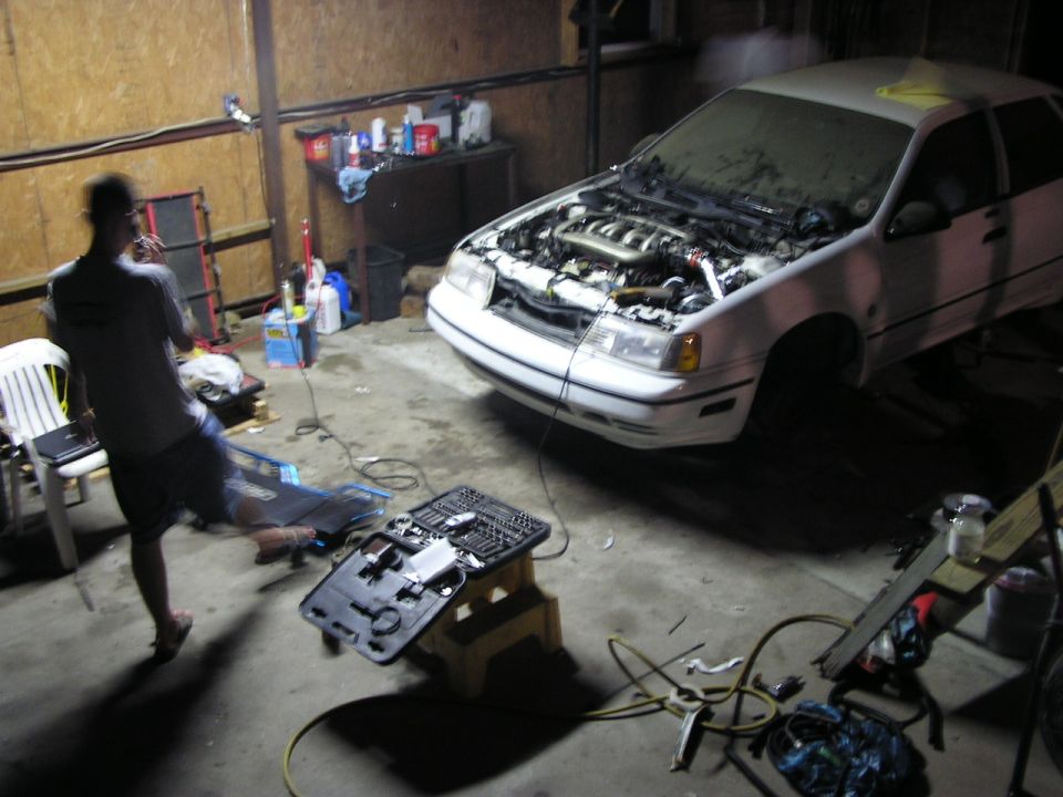 White 1993 Ford Taurus sedan with hood open, front 3/4 view, in a garage