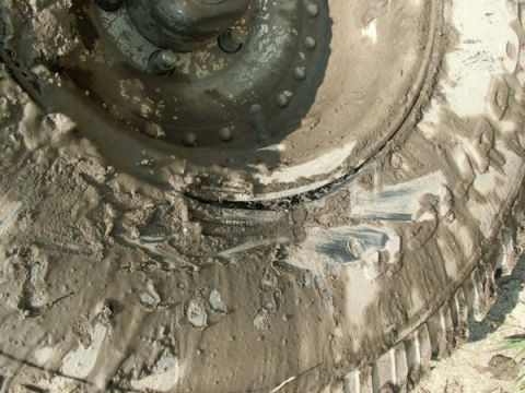 1988 Ford Bronco - This close-up shows a heavily mud-caked tire and wheel, obscuring any specific vehicle details.