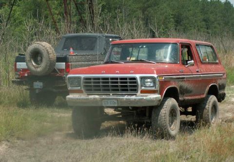 1988 Ford Bronco - A red Ford Bronco is seen off-road with another vehicle behind it. The grille suggests a 1978 model year.