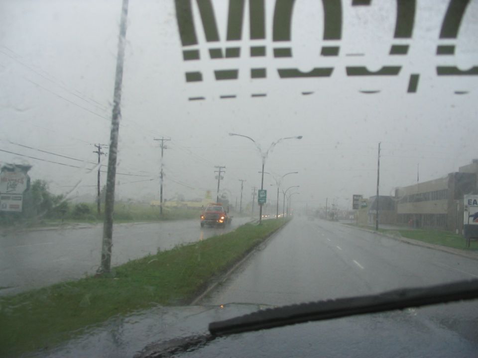 Interior view of a vehicle driving on a rainy day, with a truck visible ahead