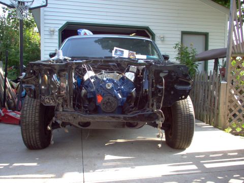 1970 Ford Ranchero - The front end of a 1970 Ford Ranchero is shown with its engine exposed, revealing a blue engine block and black exterior.