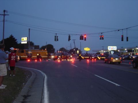 1998 Ford Taurus - Emergency vehicles respond to a traffic incident at a crossroads during twilight, with a gas station visible in the background.
