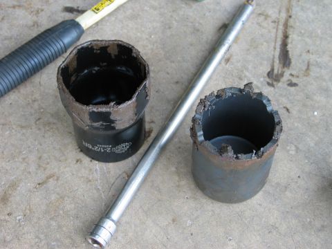 1995 Ford Bronco - Two badly chewed-up large sockets sit on a concrete floor next to a breaker bar and a ratchet handle, one marked 2-1/2" 6PT with its rim sp…