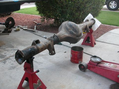 1984 Ford Bronco - A rear axle assembly is shown on jack stands, ready for overhaul, with tools and fluids nearby.