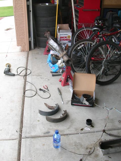 1984 Ford Bronco - Various automotive parts and tools are organized on the concrete floor of a garage, ready for maintenance.