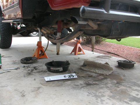 1984 Ford Bronco - The rear suspension of a 1984 Ford Bronco is disassembled for overhaul, with tools and parts scattered on the concrete.