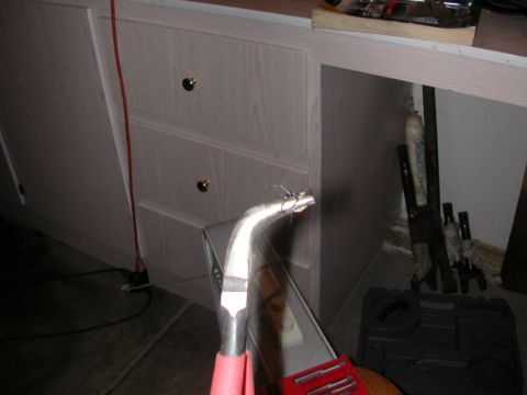 1984 Ford Bronco - A tool is held over a toolbox next to storage cabinets.