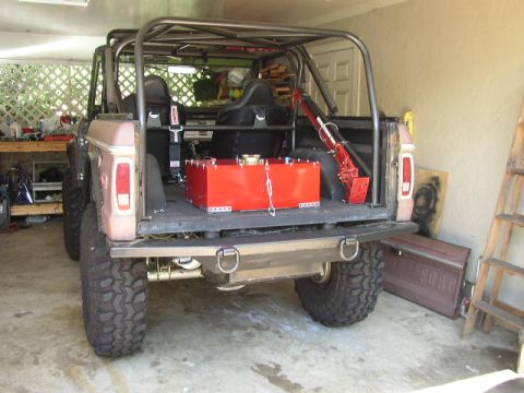 1995 Ford Bronco - This modified Ford Bronco features a custom roll cage and an auxiliary fuel tank in the bed. A detached Ford door is visible leaning agains…