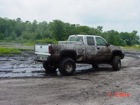 1995 Dodge 1500 - A lifted pickup truck is covered in mud after driving through a wet, off-road area.