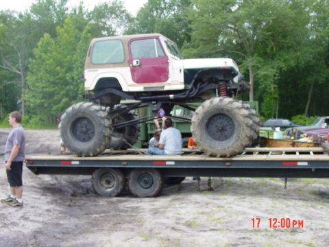 1995 Dodge 1500 - Monster truck with custom modifications is being transported on a flatbed trailer.