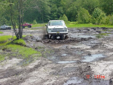 1995 Dodge 1500 - Multiple trucks navigate a muddy off-road course.
