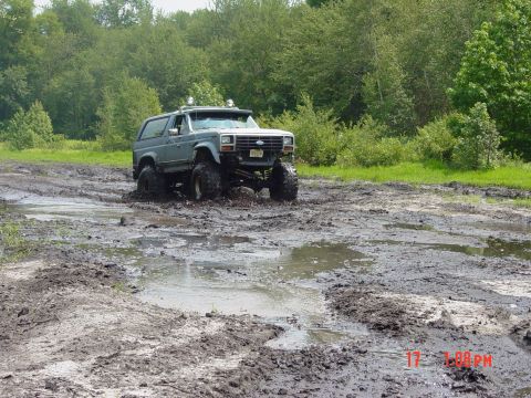 1995 Dodge 1500 - This modified Ford Bronco is navigating a muddy off-road course.