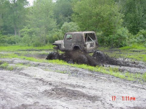 1995 Dodge 1500 - Modified Jeep deep in mud during off-road event. Watermark indicates SUPERMOTORS.