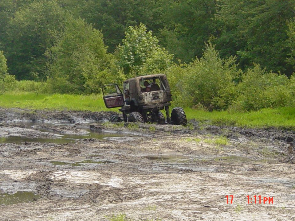 Off-road vehicle with open door stuck in mud pit