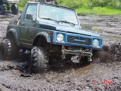 1995 Dodge 1500 - Off-road vehicle navigates a challenging muddy terrain, with another vehicle partially visible in the background.